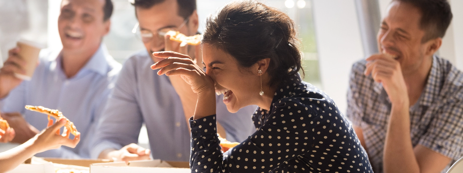 Coworkers laugh over pizza