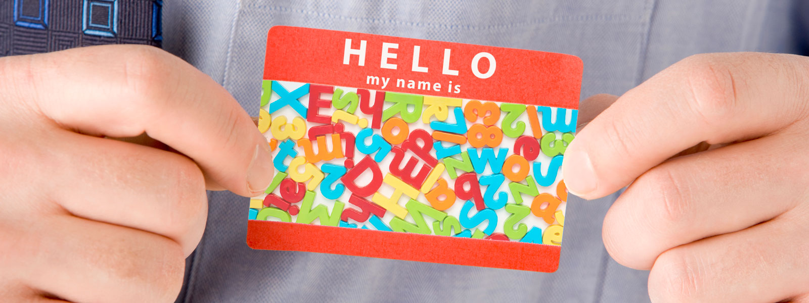 Hands hold a name tag containing a jumble of letters