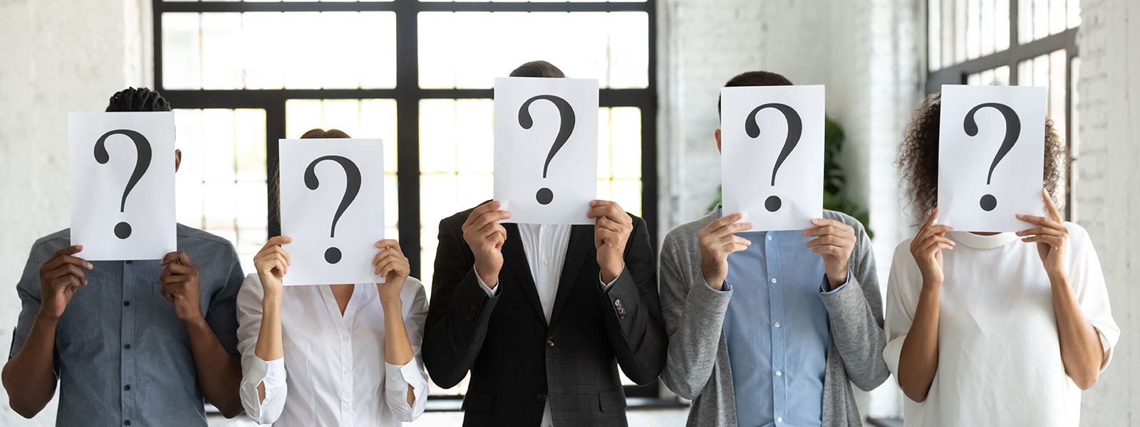 Five people hold printed sheets with question marks in front of their faces