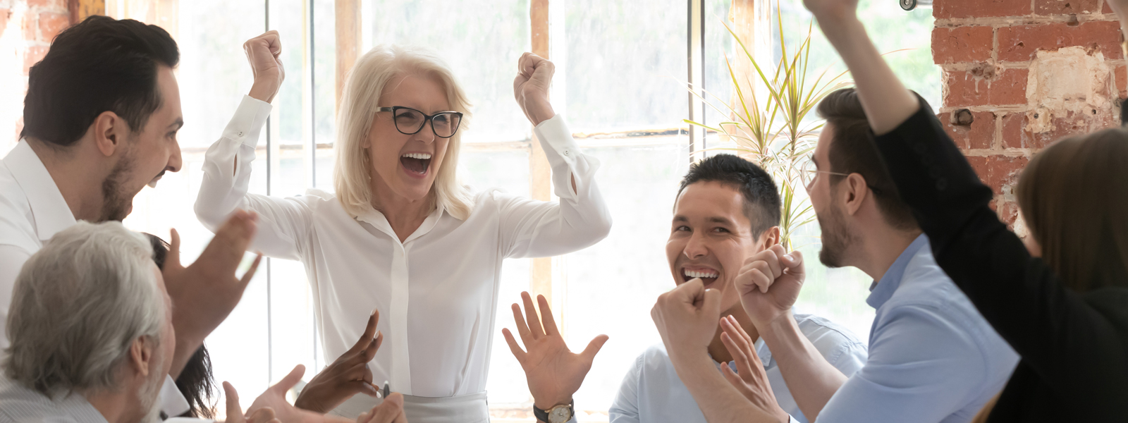 A photo of a mature businesswoman leading a cheer amongst her colleagues