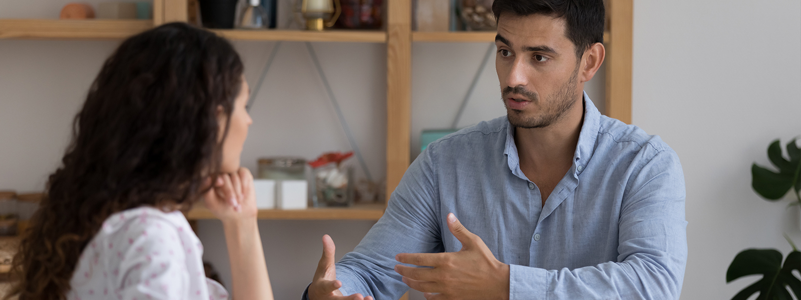 A man and woman engaged in a conversation while seated at a table.