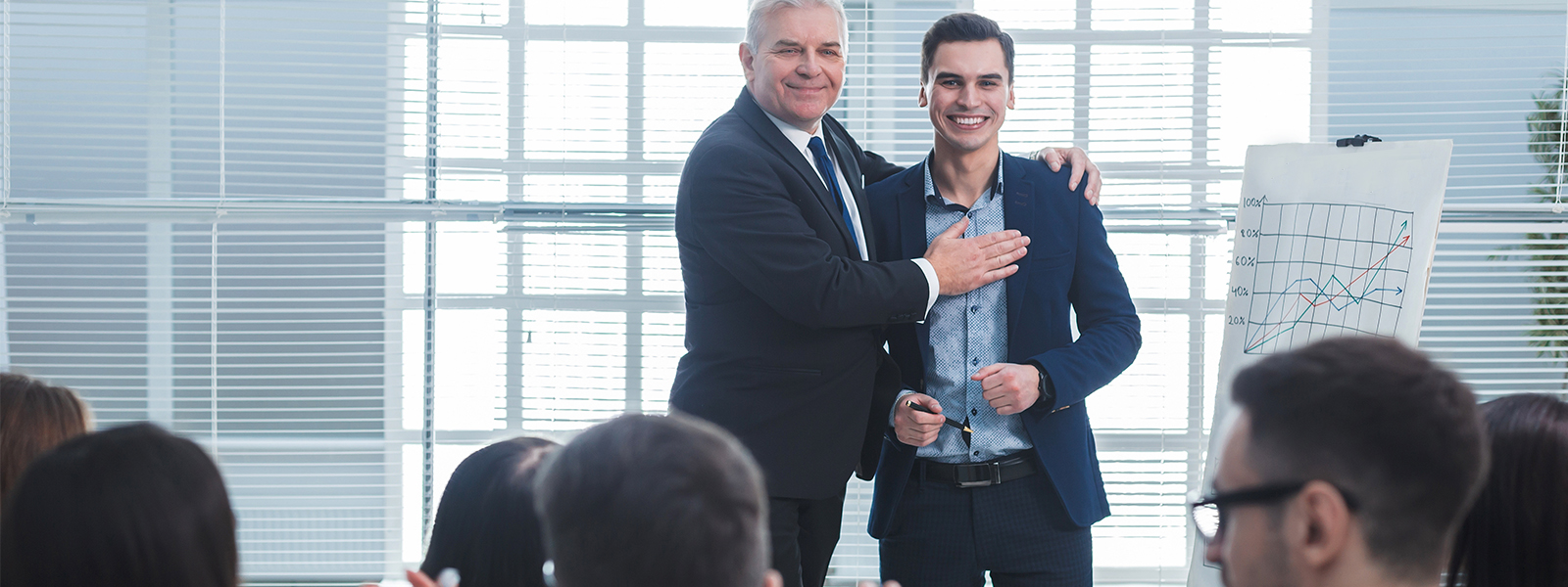 Two businessmen in suits presenting to a group of people.