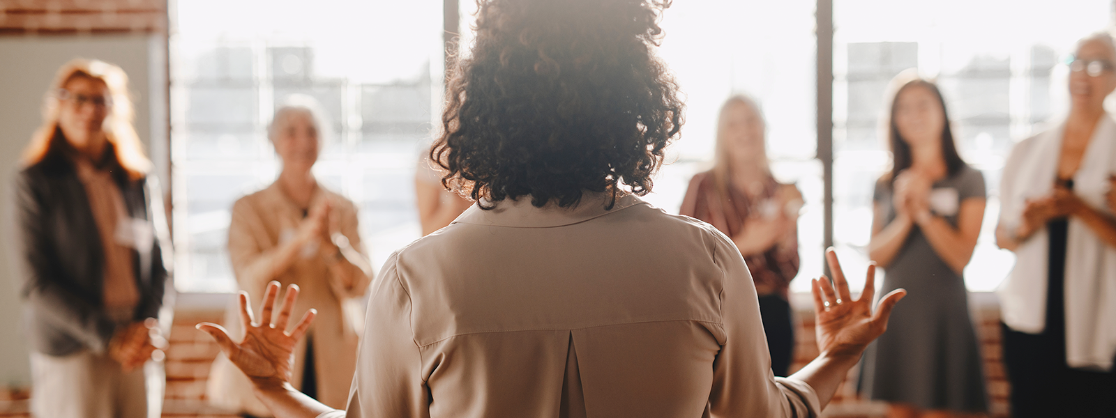 A woman confidently addressing a group of people, commanding attention and engaging in public speaking.