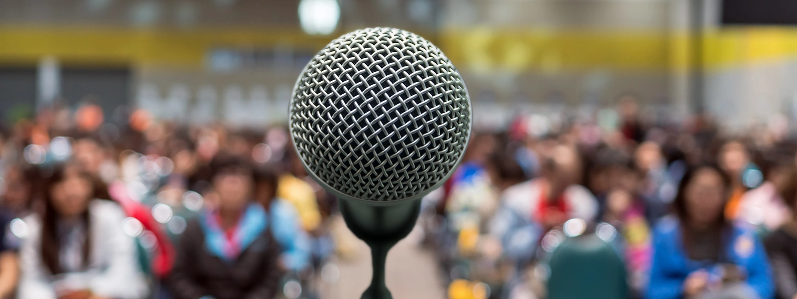 a close up photo of a microphone with a large crowd in the background