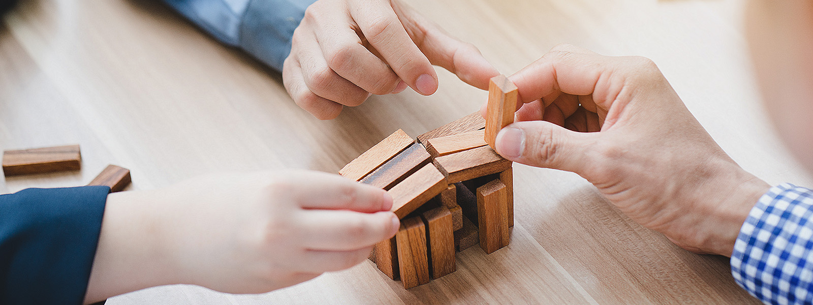 Hands solving a wooden puzzle together