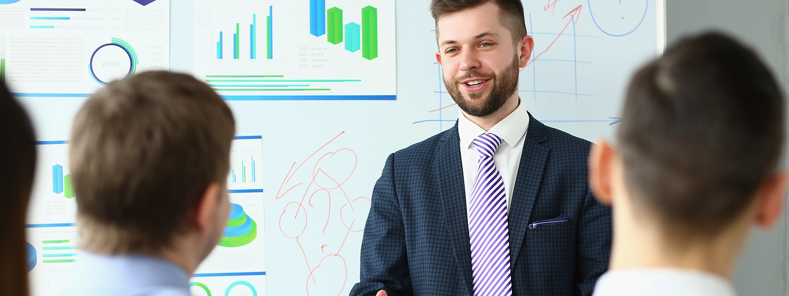 A man speaking to an audience in front of charts