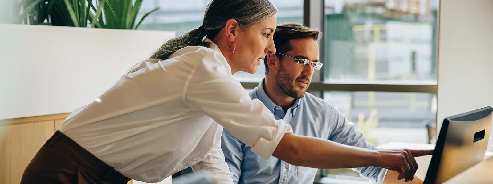A photo of a woman pointing out something to a coworker on a computer screen