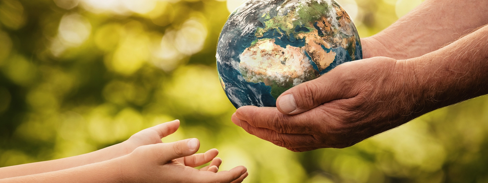 a photo of a pair of old hands handing a globe to a pair of young hands