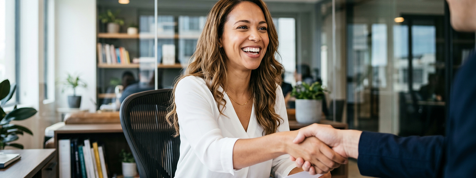 Smiling business professionals shaking hands after successful client meeting